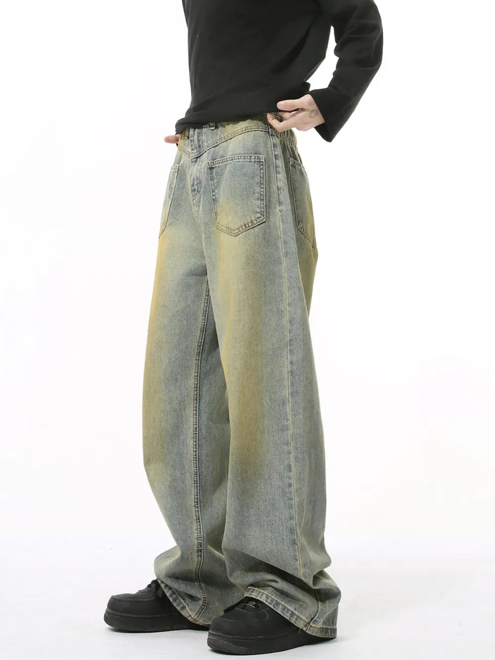 Distressed denim jeans in a medium wash with a relaxed fit and yellowed accents.