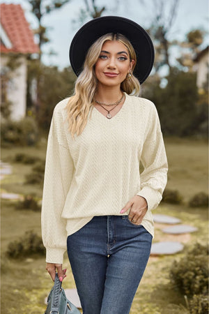 Ivory textured cable knit v-neck sweater with long sleeves.