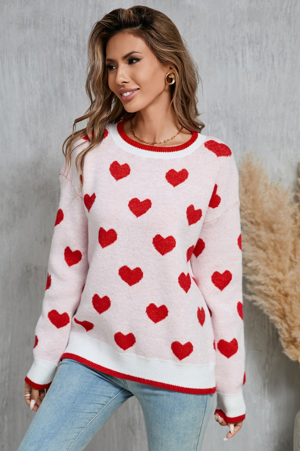 Pink crewneck sweater with red hearts pattern, white and red trim, acrylic knit.