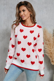 Pink crewneck sweater with red hearts pattern, white and red trim, acrylic knit.