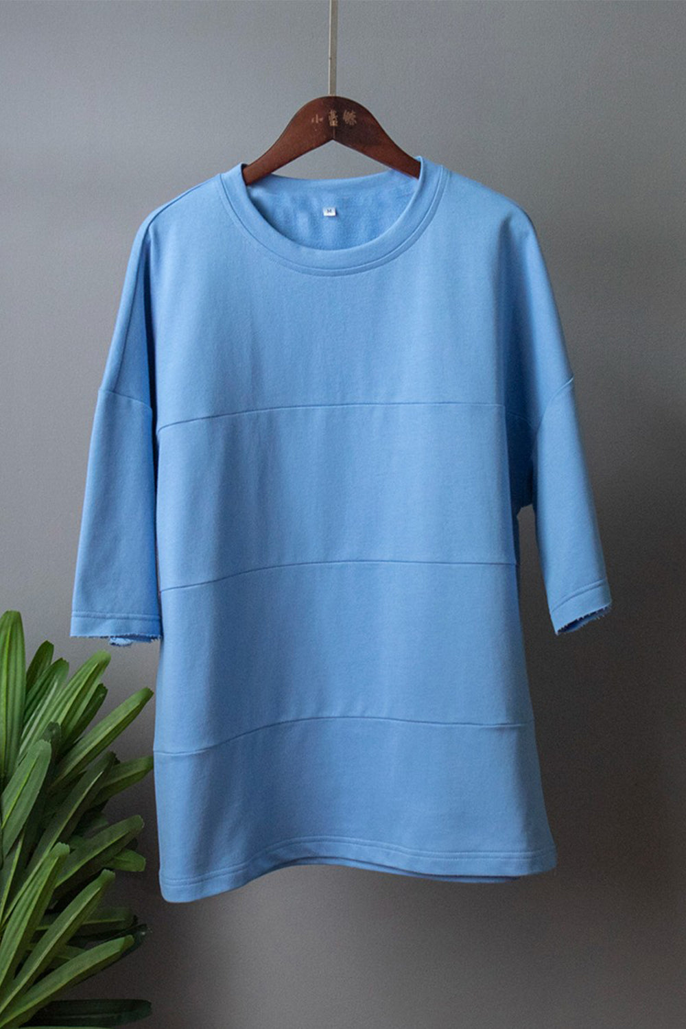 Pastel blue relaxed fit sweatshirt with horizontal seam details and raw hem sleeves.