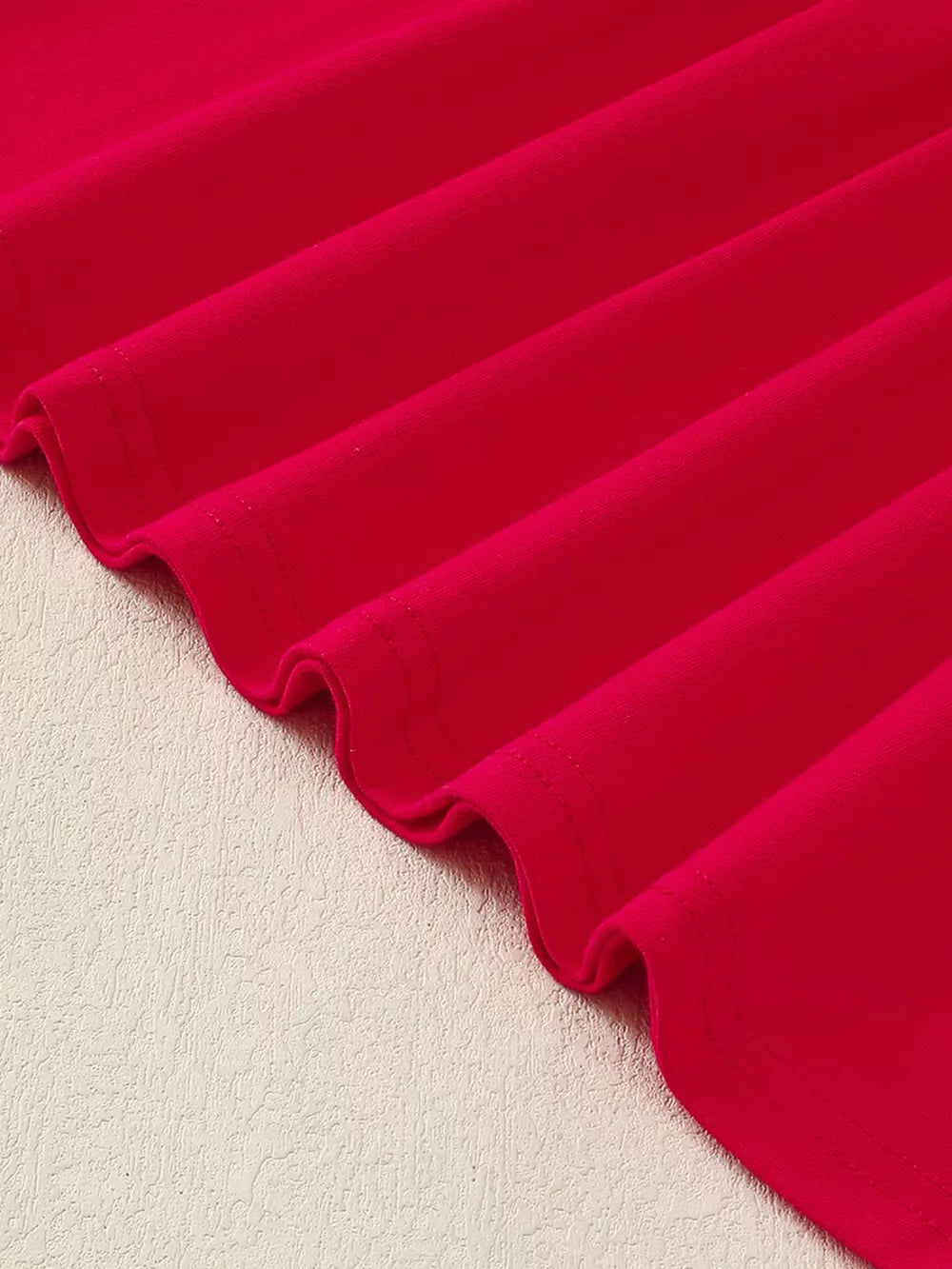 Red baby dress fabric detail with subtle texture and wavy hem