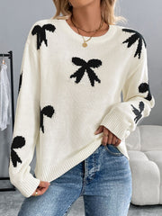 Cream knit crewneck sweater with scattered black bow pattern, long sleeves, and crew neckline.