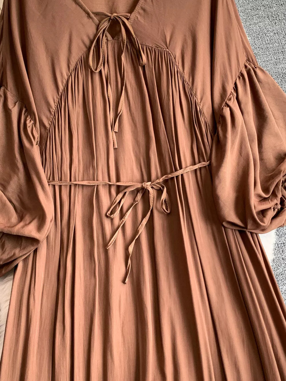 Brown bohemian maxi dress with balloon sleeves, tie neckline, and cinched waist.