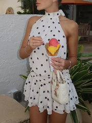 White polka dot halter neck mini dress with ruched waist and tiered skirt.
