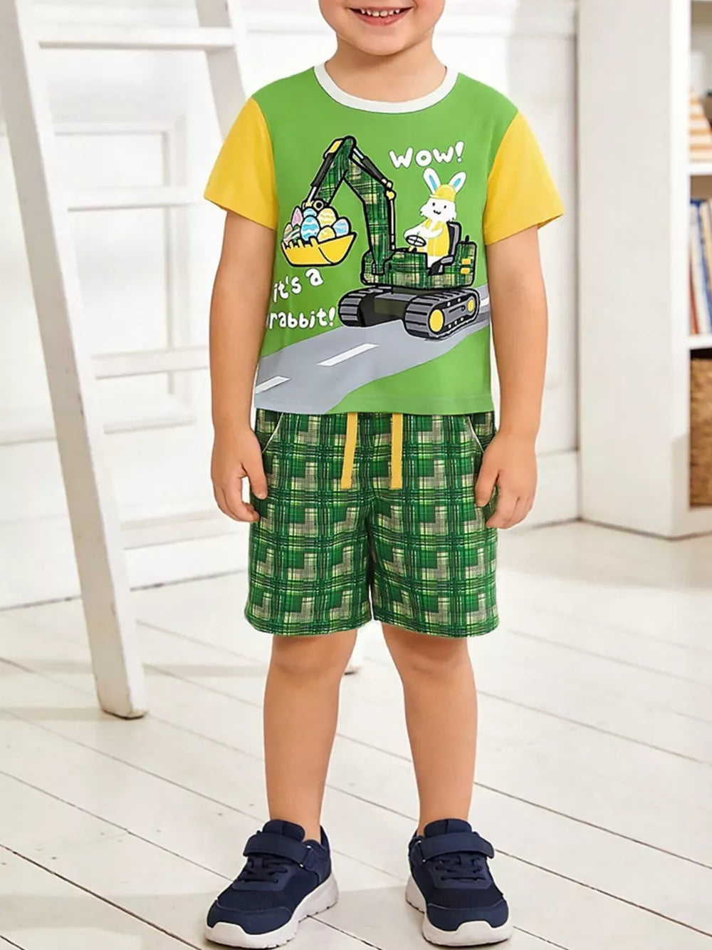 Baby boys green cotton tee with excavator graphic and yellow sleeve, paired with green plaid shorts.