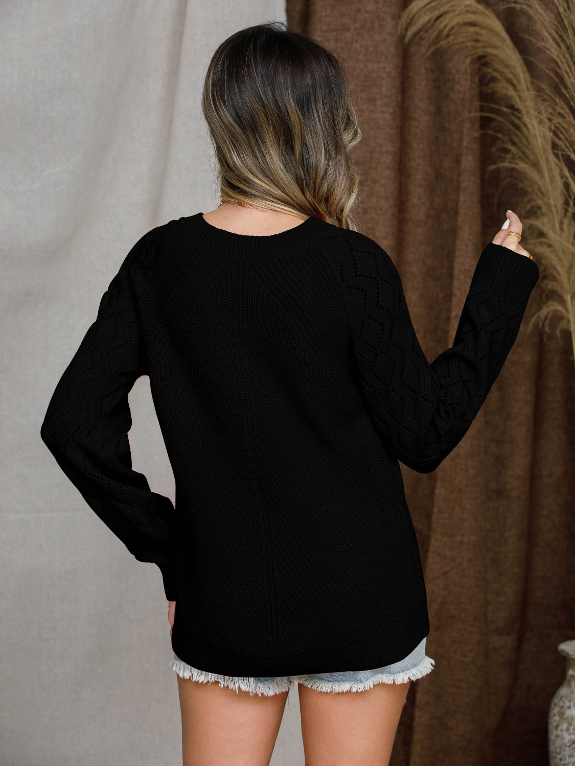 Black diamond-cut raglan knit sweater with crew neck and long sleeves.