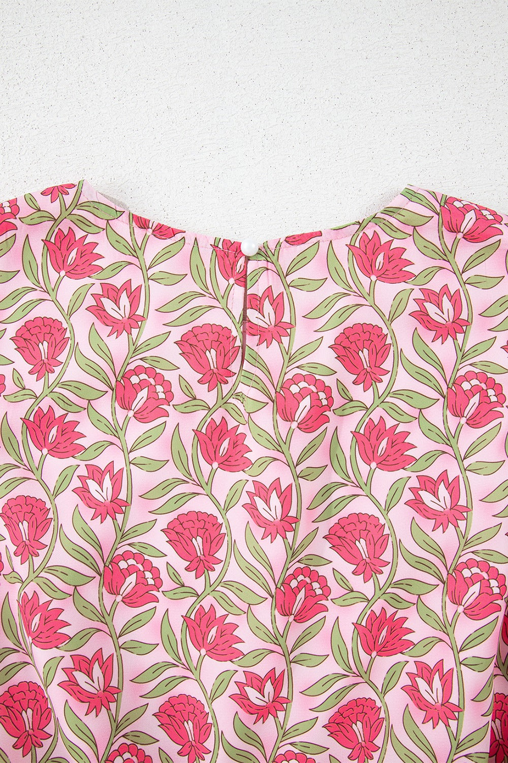 Dusty pink floral print crop top with a round neckline and button closure.