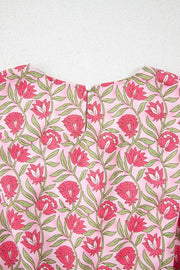 Dusty pink floral print crop top with a round neckline and button closure.