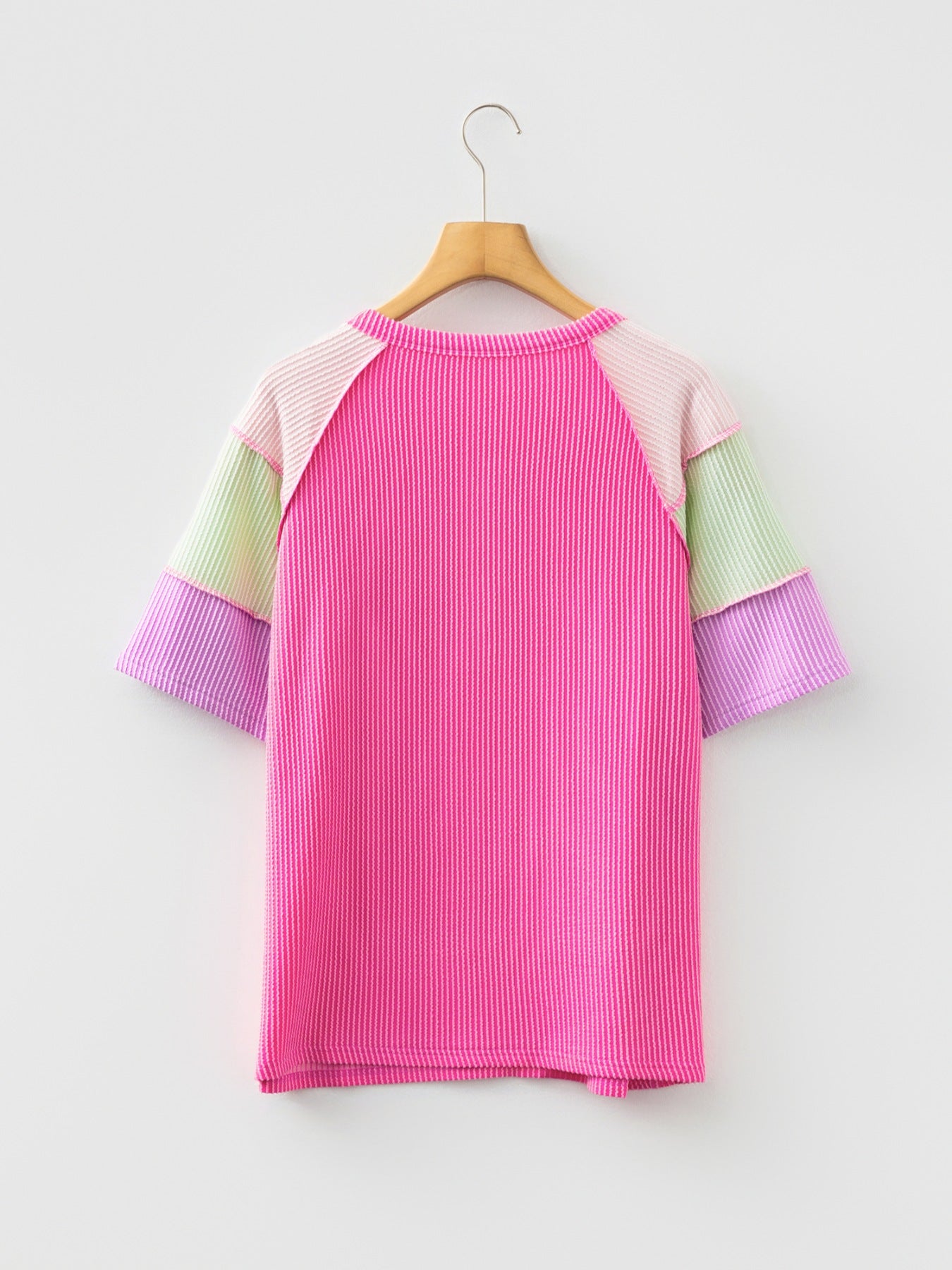 Color block t-shirt with pink, purple, green, and light pink patchwork sleeves and ribbed texture.