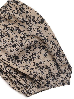 Smocked bodice floral palazzo jumpsuit in taupe with black floral print and elastic cuff detail.