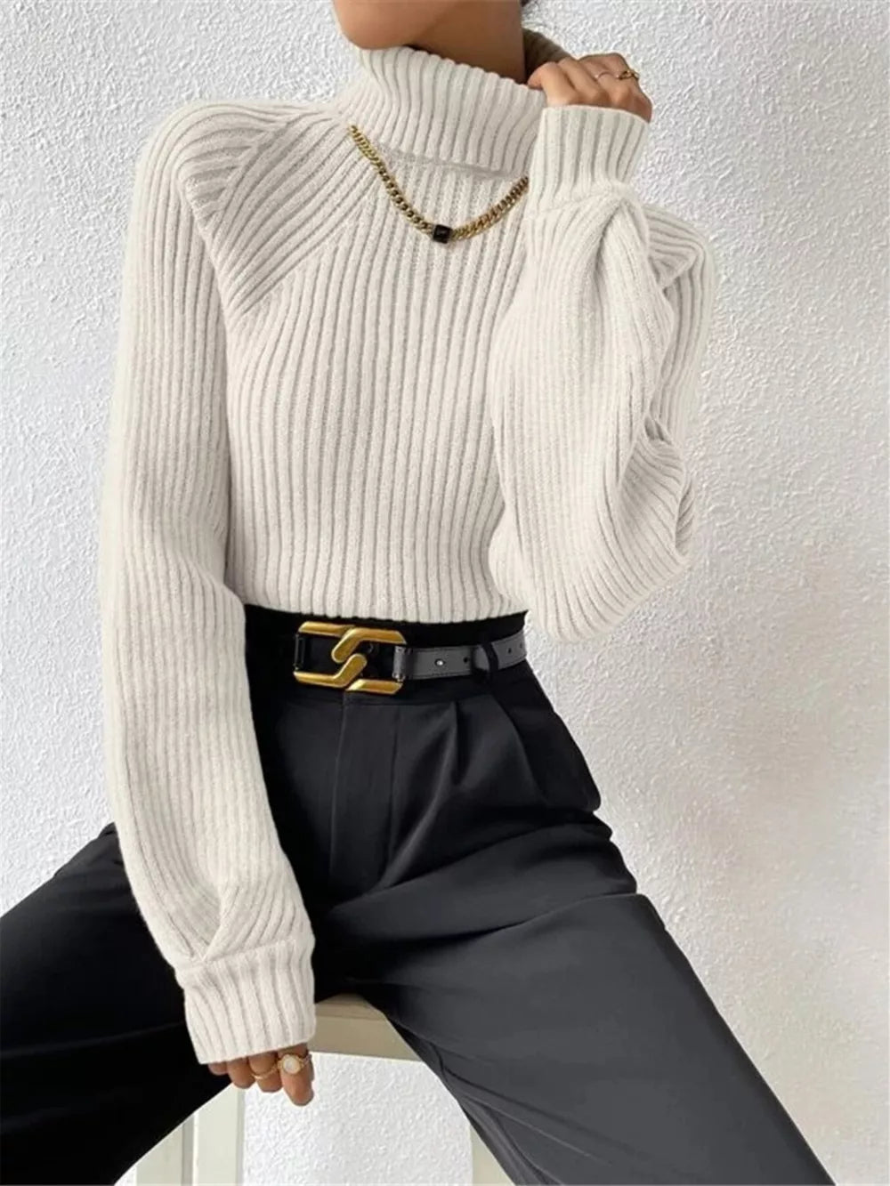 White ribbed turtleneck sweater with long sleeves and a high neck.