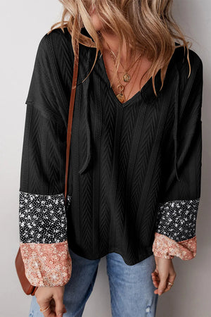 Black textured henley blouse with contrast floral print sleeves and v-neck.