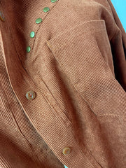 Brown corduroy shirt jacket with green studded buttons and chest pocket detail.
