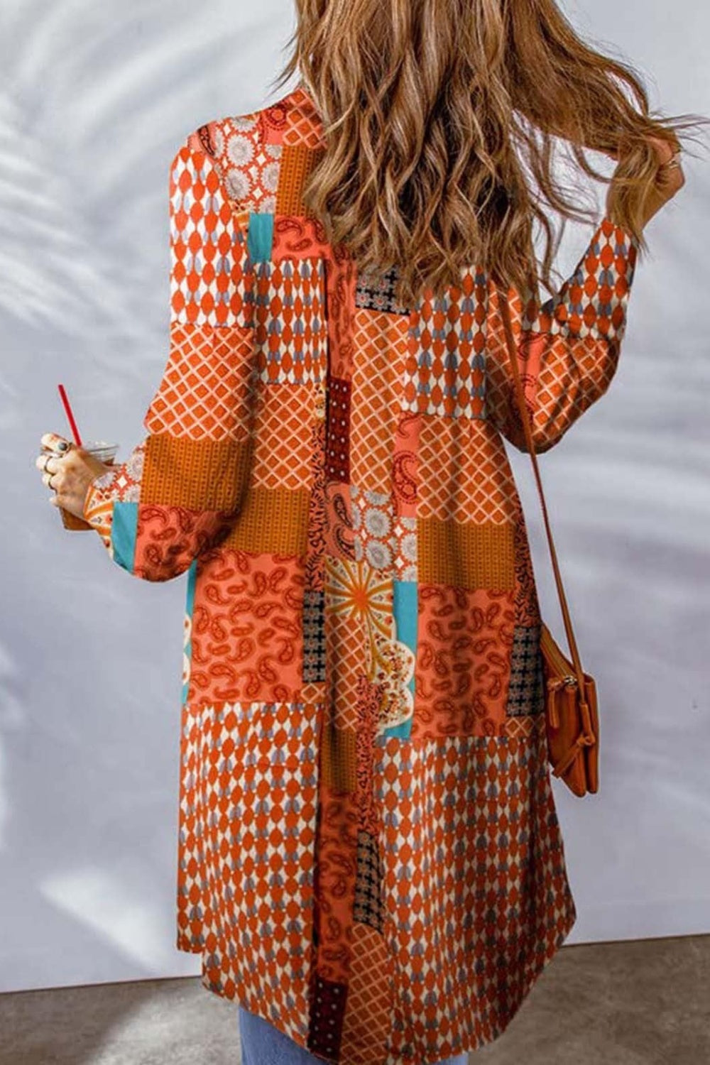Patchwork print duster shirt jacket in orange with paisley and geometric patterns, long sleeves, button front.