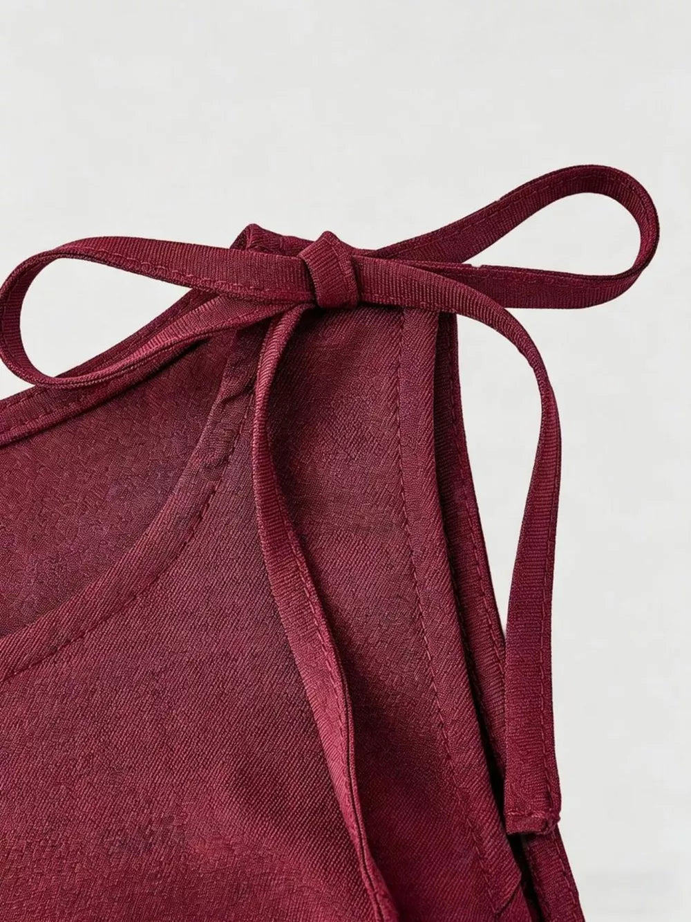 Burgundy tie-shoulder vest with subtle floral pattern and textured fabric.