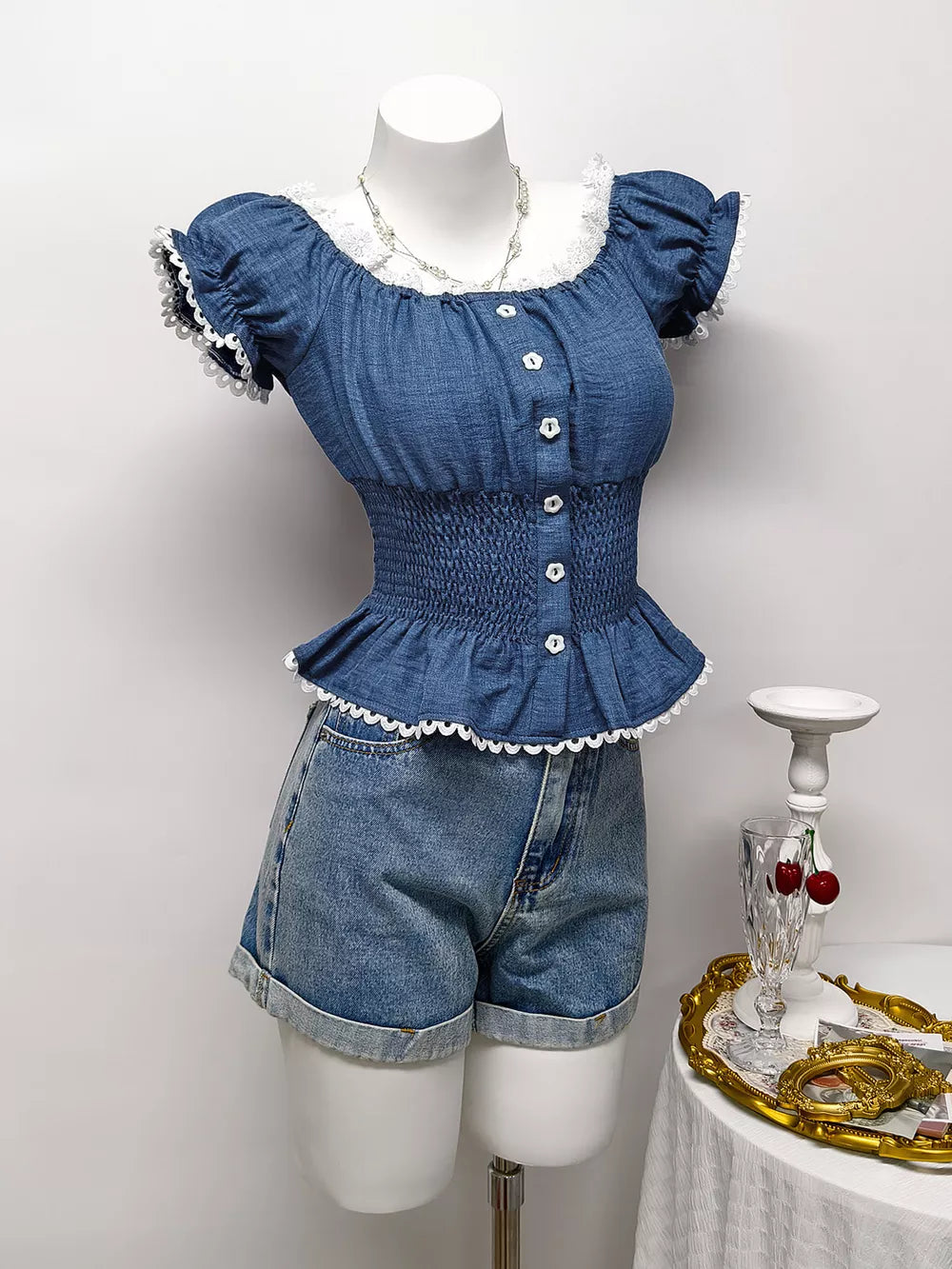 Blue ruffled smocked maternity blouse with puff sleeves, white lace trim and decorative buttons.