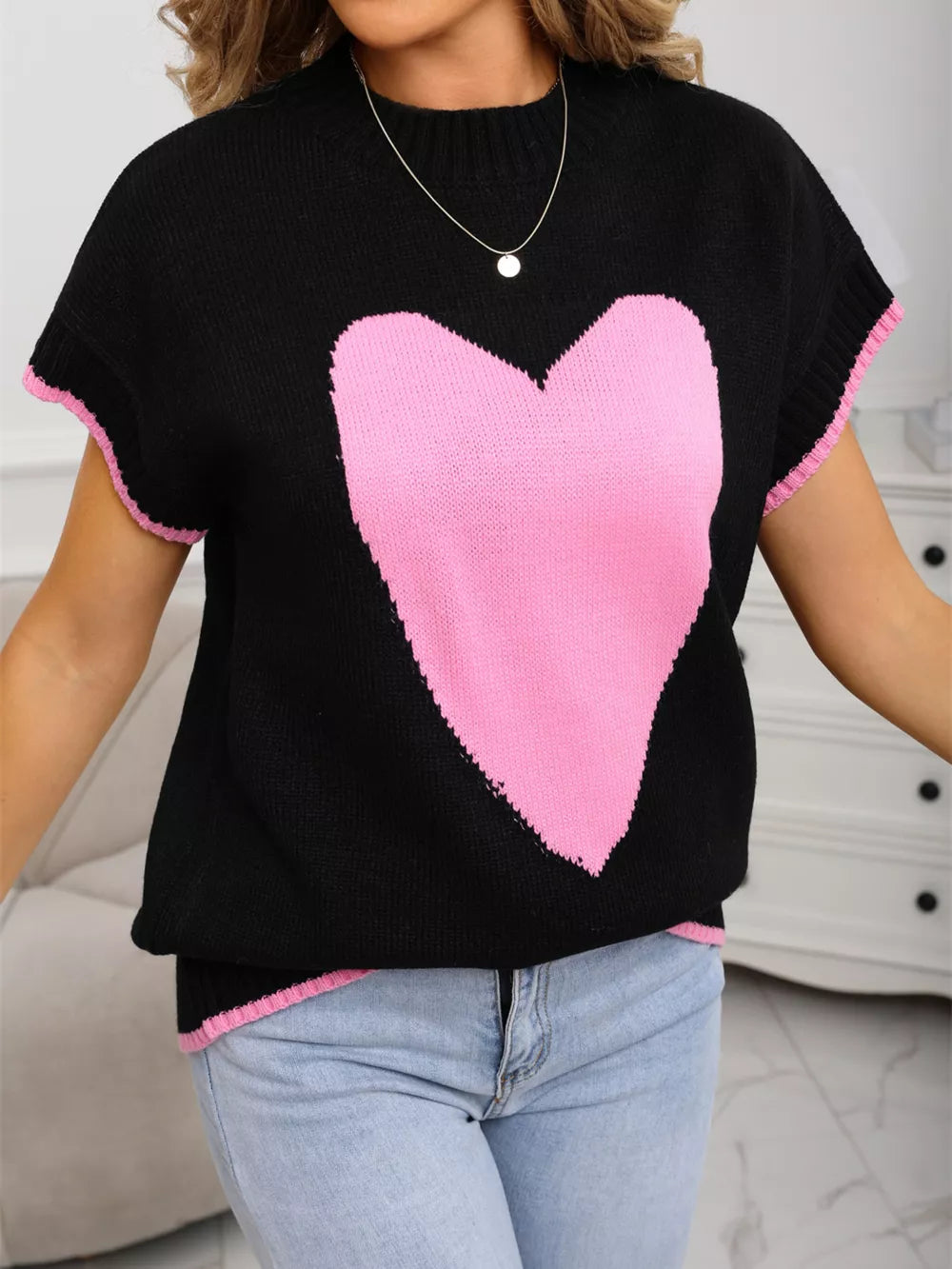 Black knit top with pink heart graphic, crew neck, short sleeves, and ribbed trim.
