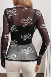 Black mesh bodysuit with white bow print and long sleeves, worn over a black camisole.