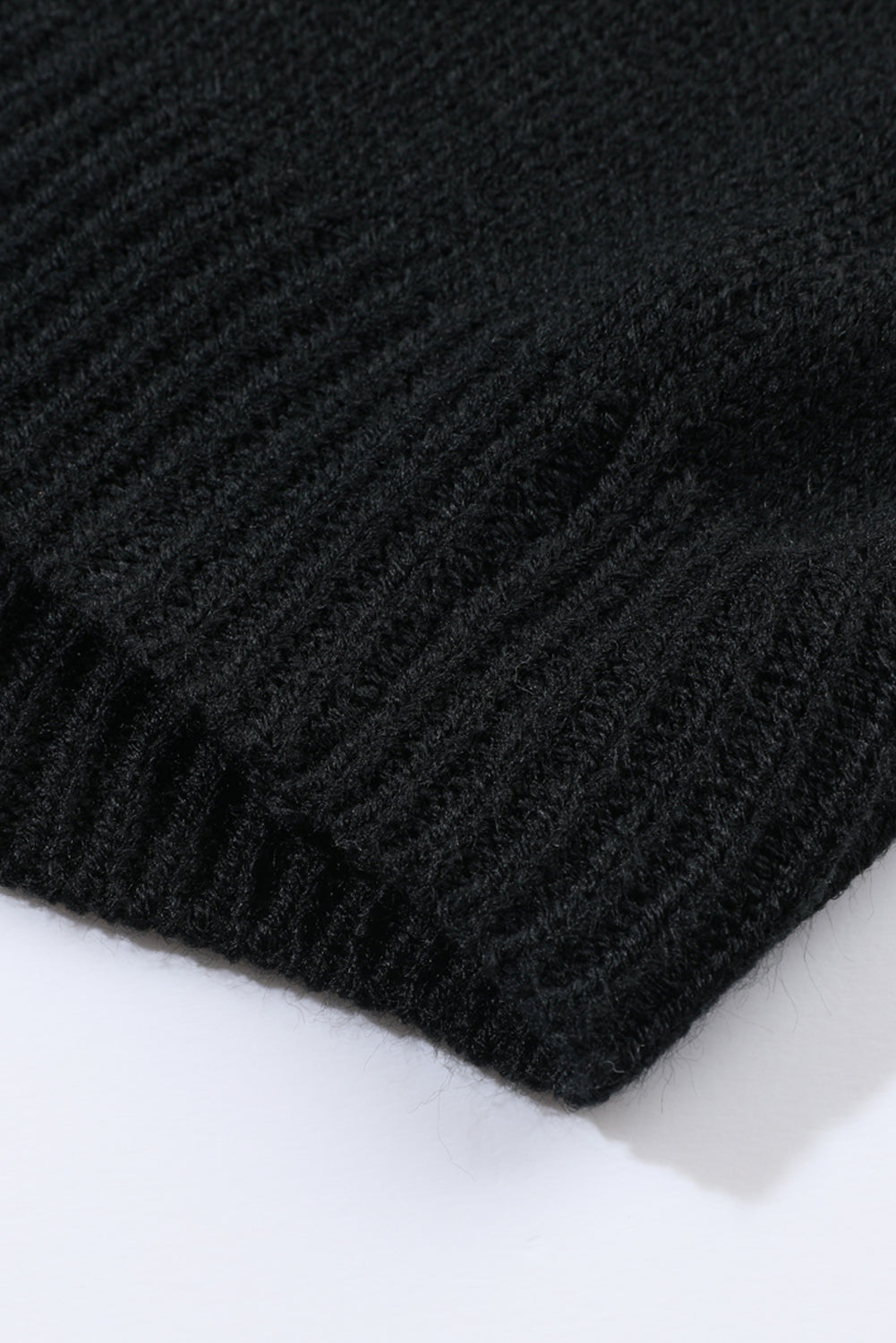 Black acrylic knit cardigan detail showing ribbed texture and hem