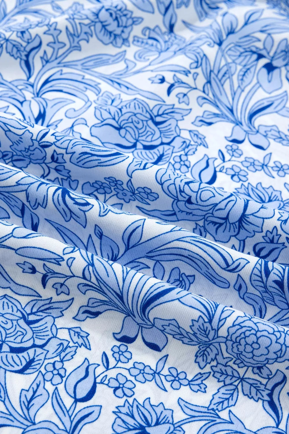 Floral pleated blouse with square neckline in blue and white floral print polyester.