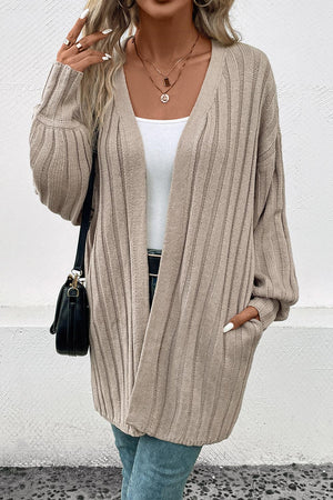 Khaki ribbed knit long cardigan with pockets and balloon sleeves, styled with a white tank top.