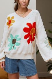 White knit sweater with embroidered floral pattern, V-neck, and long sleeves.