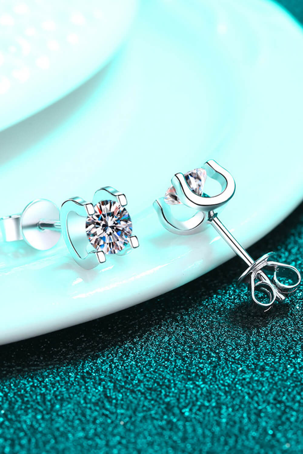 Silver moissanite stud earrings with sculpted heart and horseshoe settings.