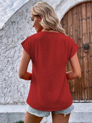 Textured red cap-sleeve blouse with button front detail.