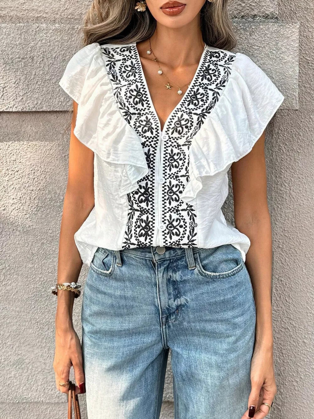 White embroidered ruffled V-neck shirt with short sleeves and button front.