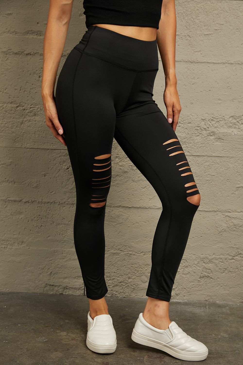 Black performance leggings with distressed knee slits and a high waist.