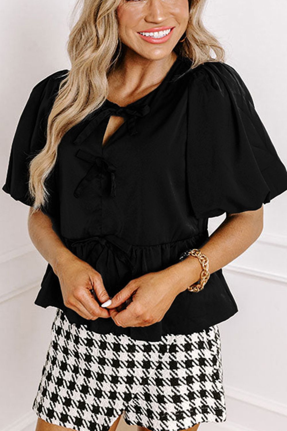 Black peplum blouse with puff sleeves, tie neck, and ruffled waist