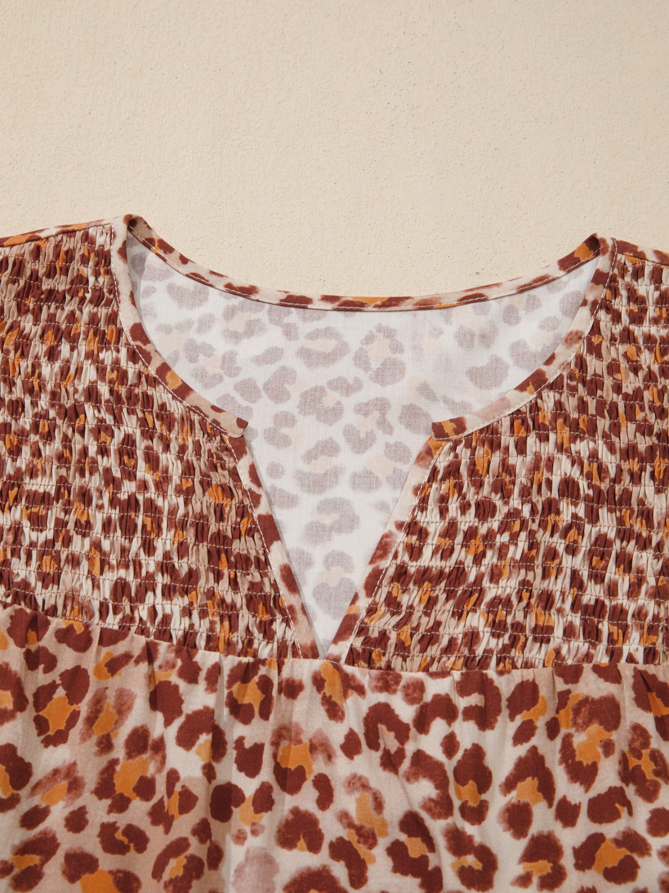 Smocked ruffled print blouse with V-neck and animal print pattern.
