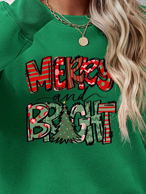Green crewneck sweatshirt with Merry and Bright Christmas graphic and festive tree detail.