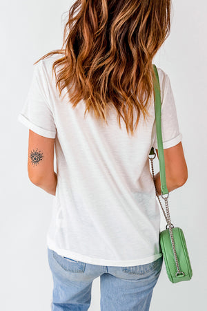 White graphic tee with rolled sleeves and a subtle eye tattoo on the arm.