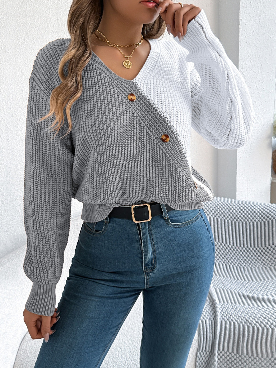 Asymmetrical colorblock knit sweater in gray and white with button detail.