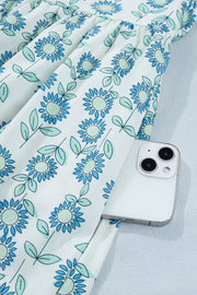Floral print cotton blend dress in pastel blue with cap sleeves and a notched neckline, showing a side pocket.
