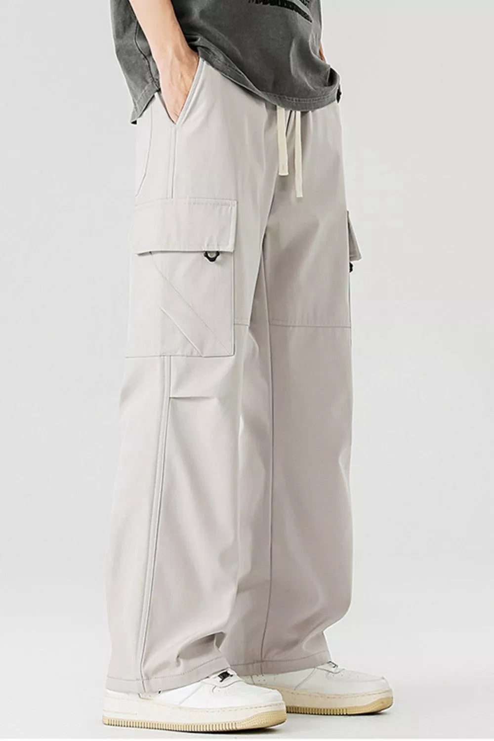 Men's beige cargo pants with multiple pockets and drawstring waist.