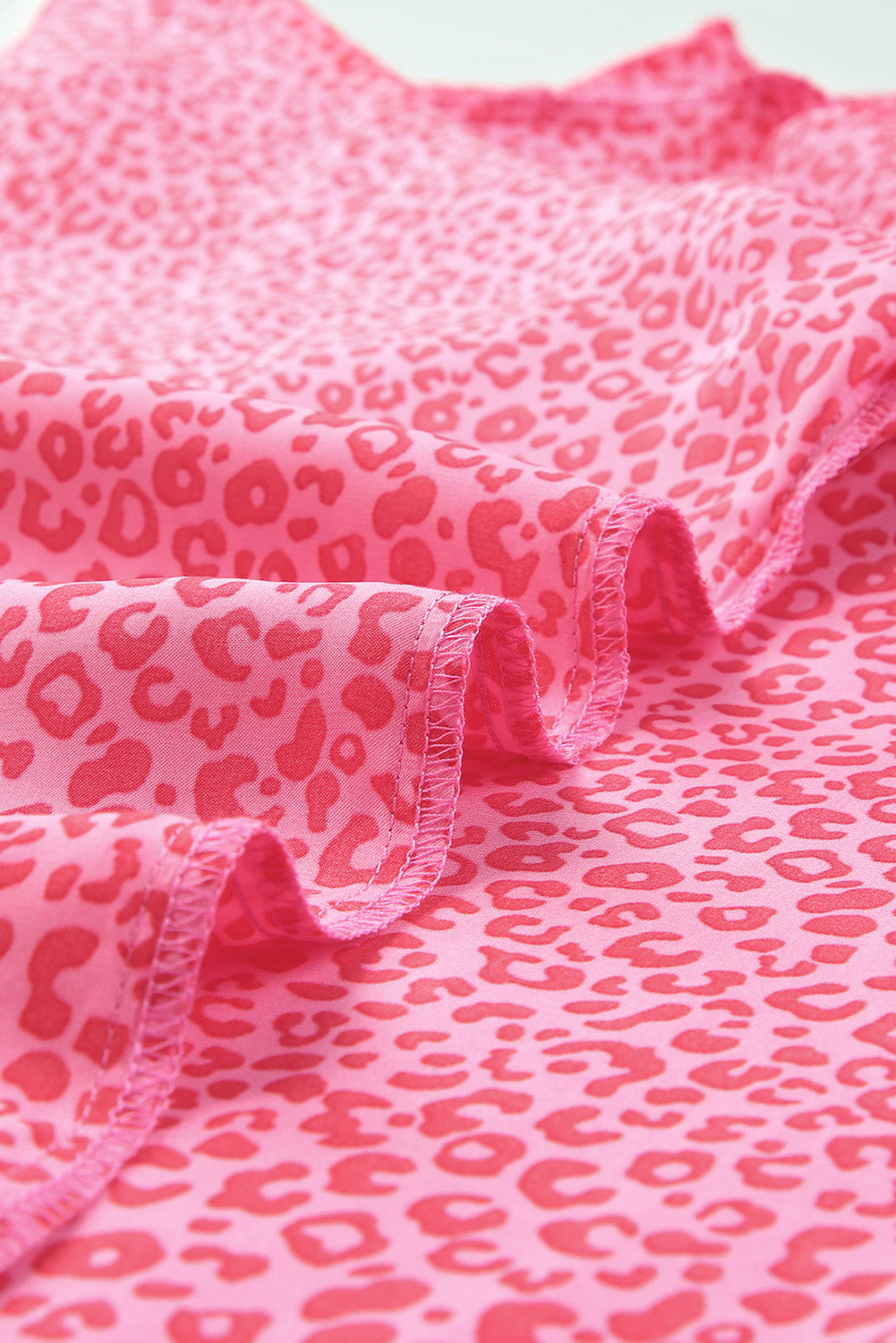 Pink leopard print blouse with smocked sleeve detail and ruffled hem.