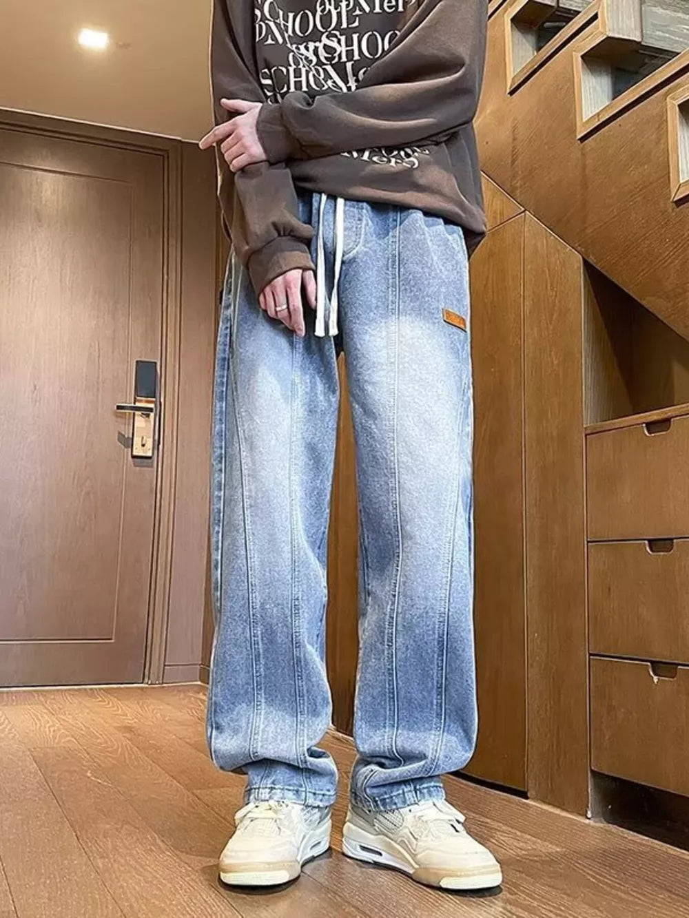 Men's blue vintage wash straight-leg jeans with drawstring and vertical seam detail.