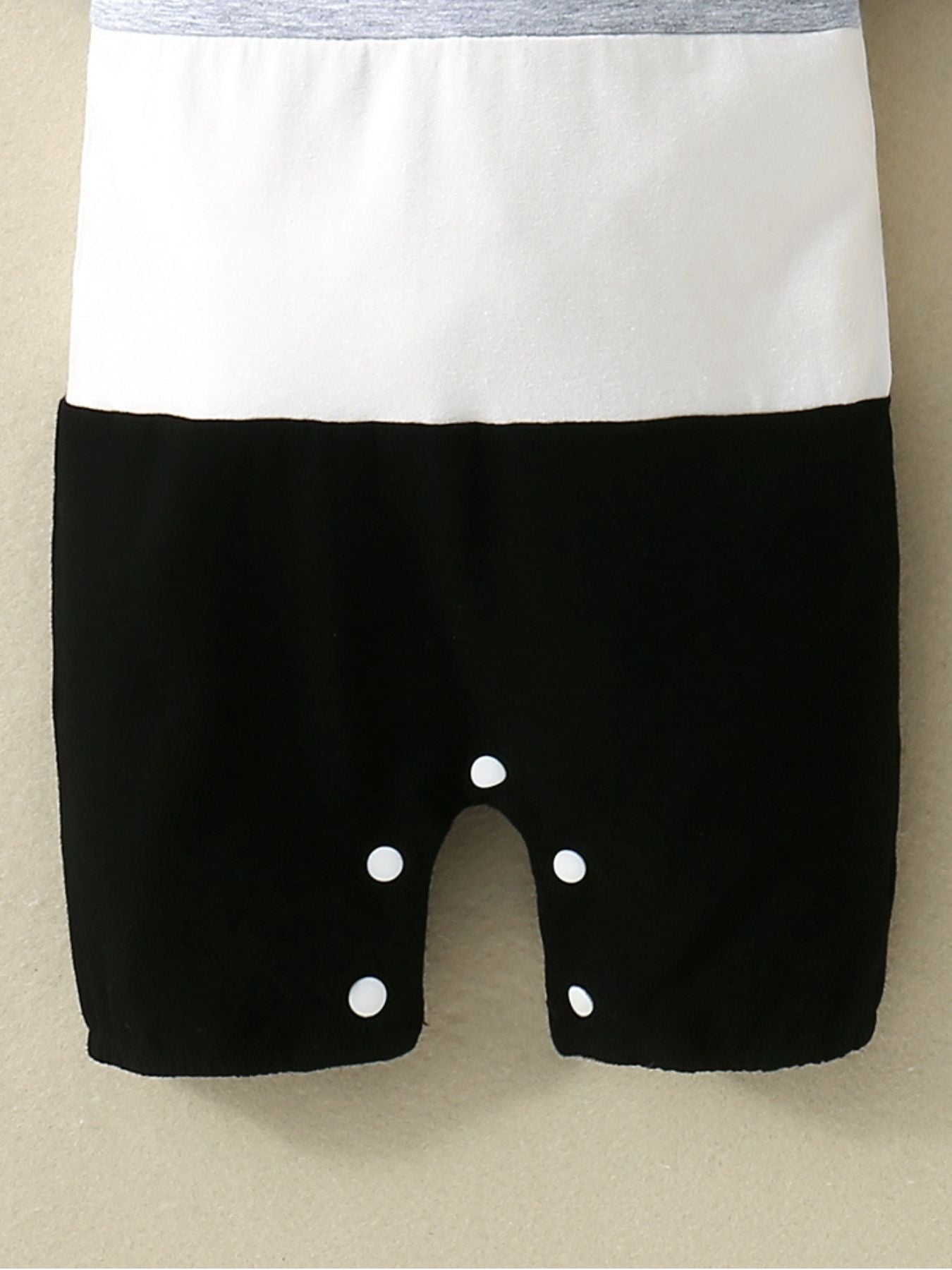 Baby cotton one-piece with color block gray, white, and black panels and snap closure.