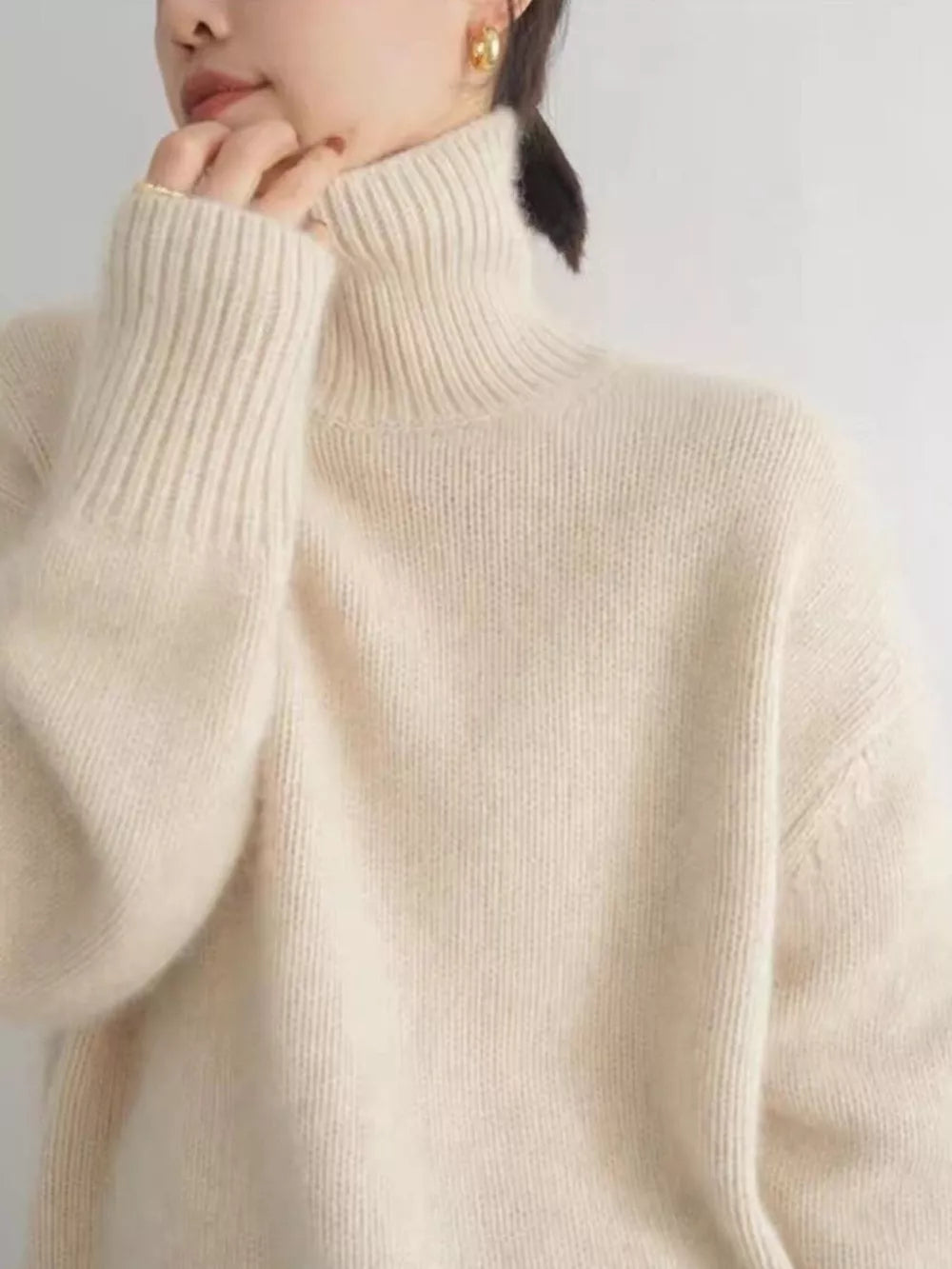 Cozy apricot knit turtleneck sweater with dropped shoulders and ribbed cuffs.