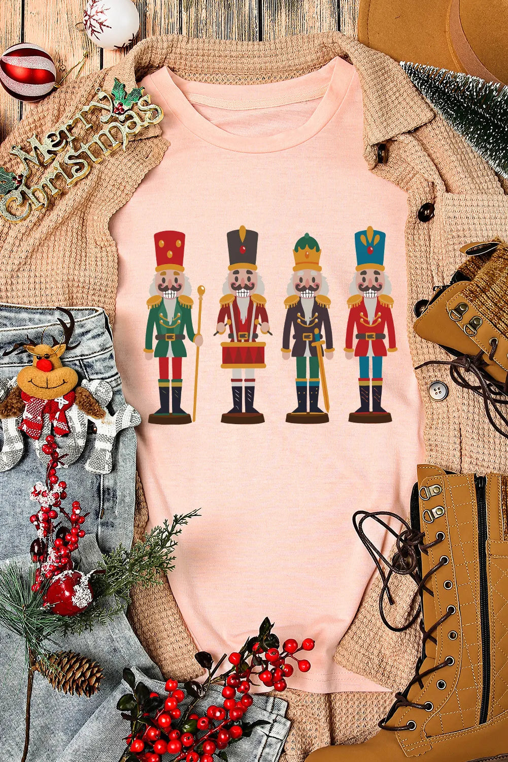 Blush pink t-shirt with a graphic print of four nutcracker soldiers in colorful uniforms.