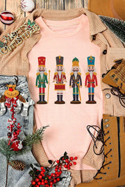 Blush pink t-shirt with a graphic print of four nutcracker soldiers in colorful uniforms.