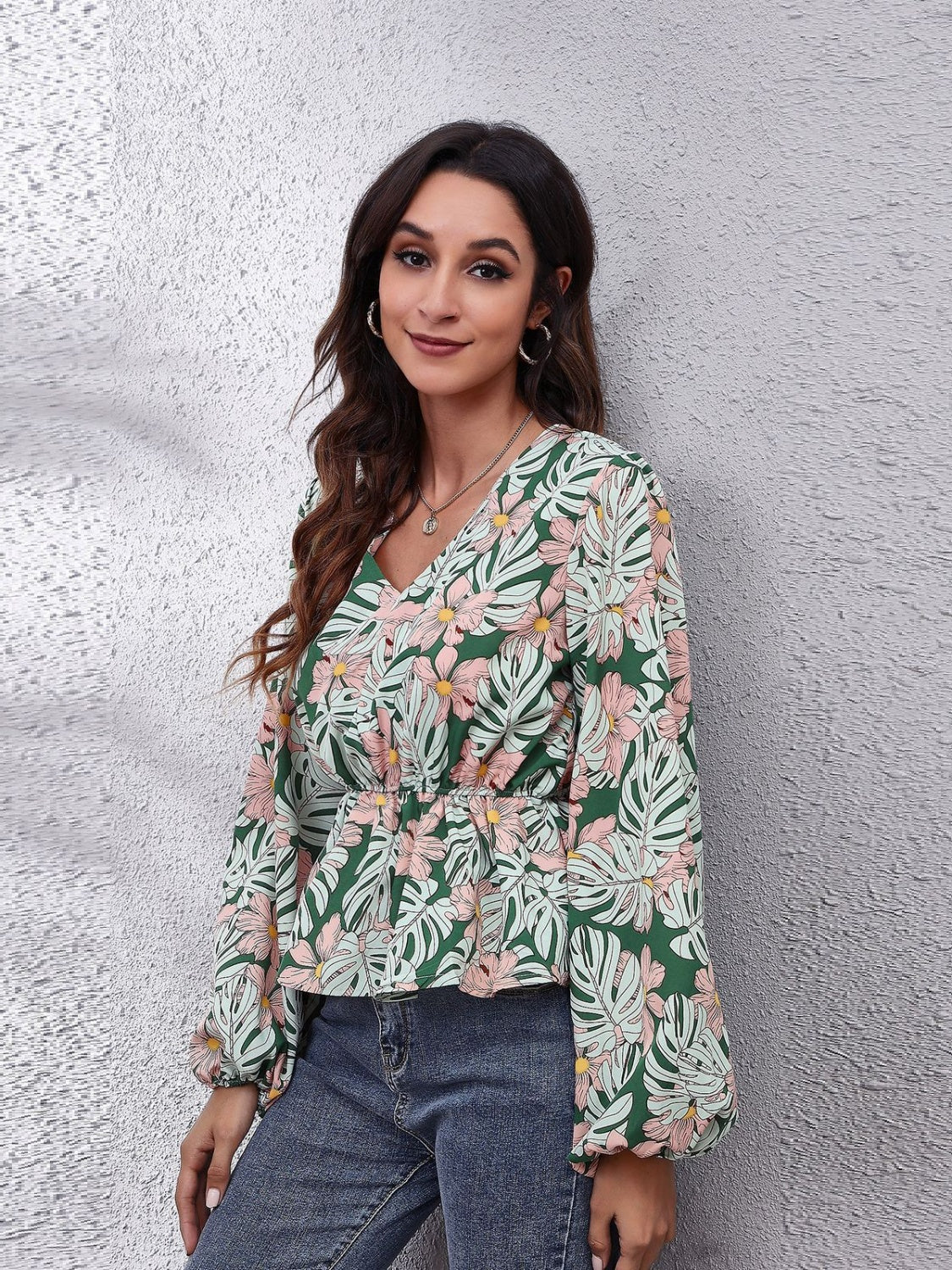 Floral peplum blouse with V-neck, gathered waist, and balloon sleeves in green with pink flowers.
