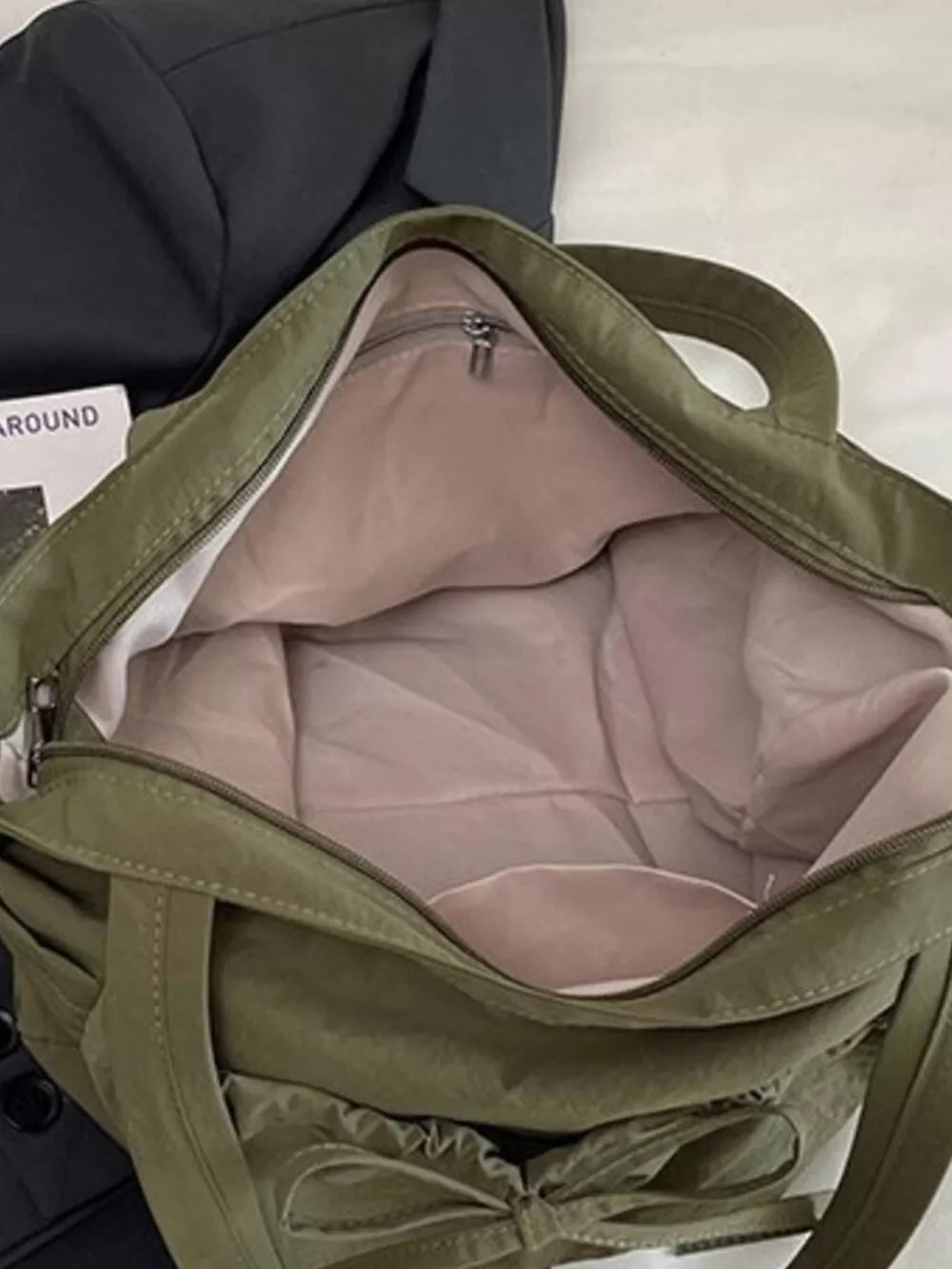 Olive green nylon tote bag with bow detail and open interior.