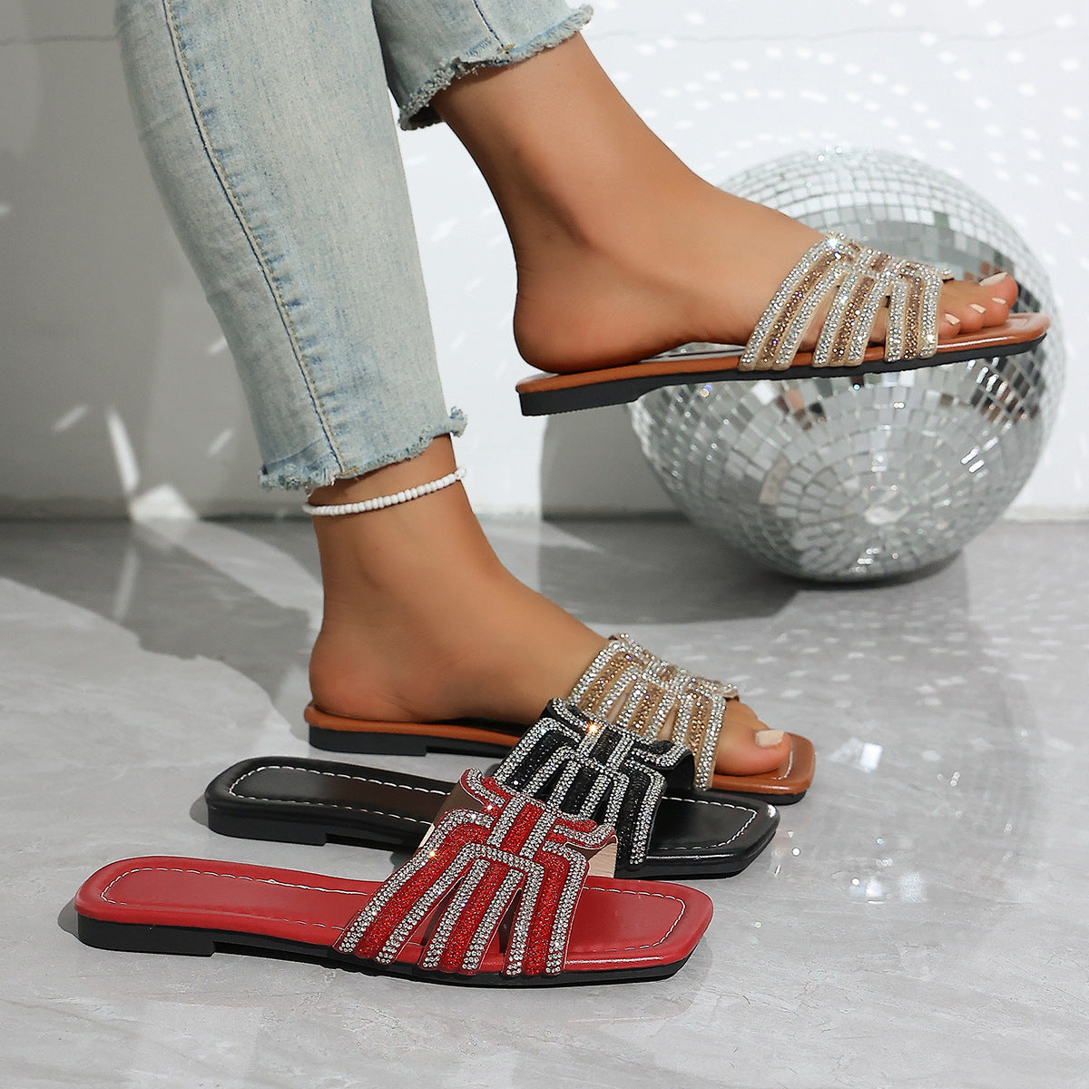 Dazzling rhinestone adorned open-toe slide sandals in black, brown, and red.