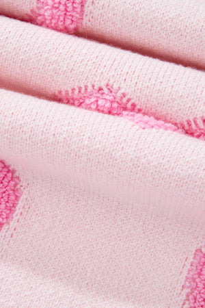 Pink knit sweater with textured heart appliqué detail and balloon sleeves.
