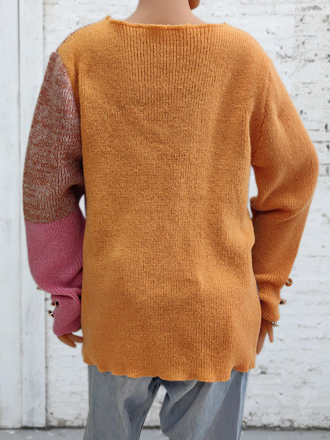 Colorblock knit sweater in sherbet orange with contrasting sleeves and button cuff detail.