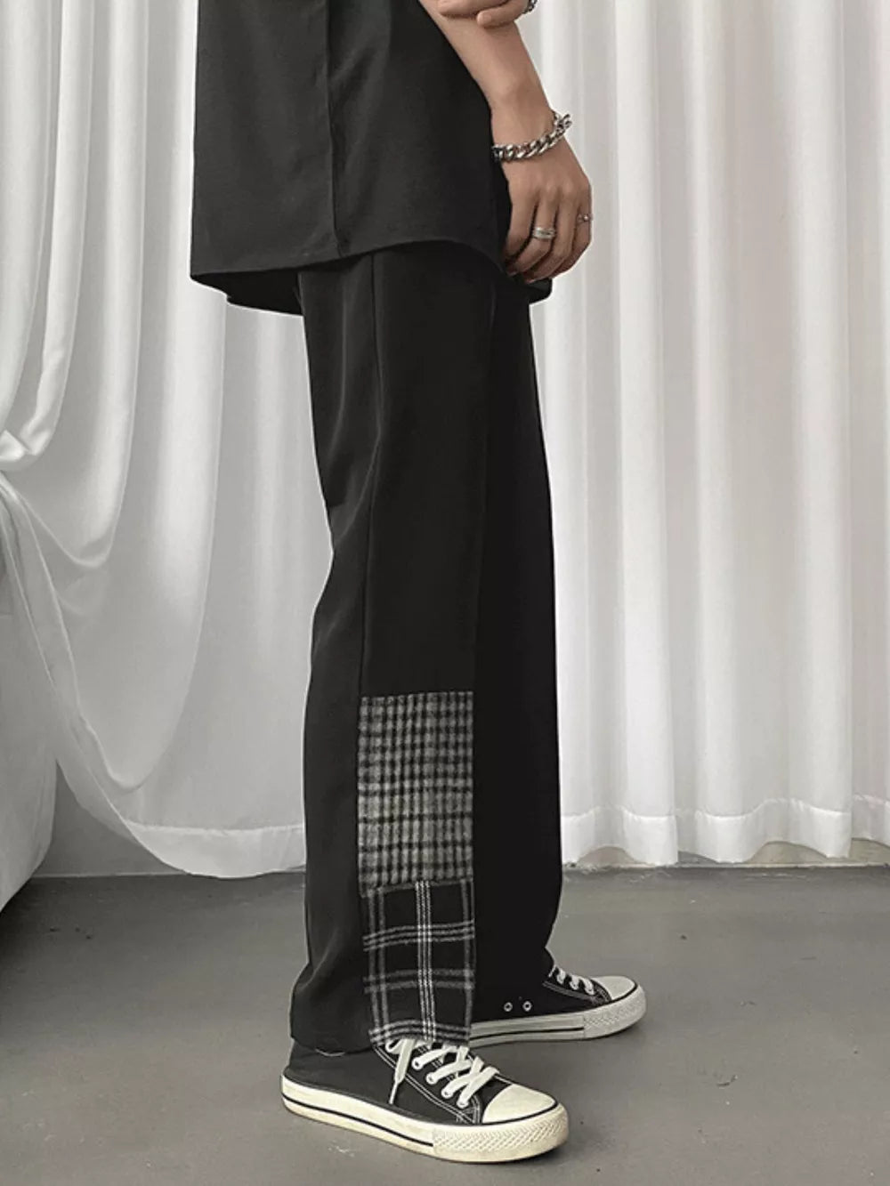 Men's black straight-leg chinos with plaid patchwork detail on the side.